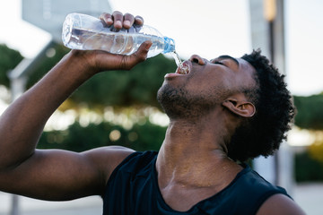 African american man drinking water after to play basketball.