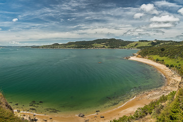 Panoramic view of the beach, white sand, blue water of the ocean and mountains and cloudy blue sky