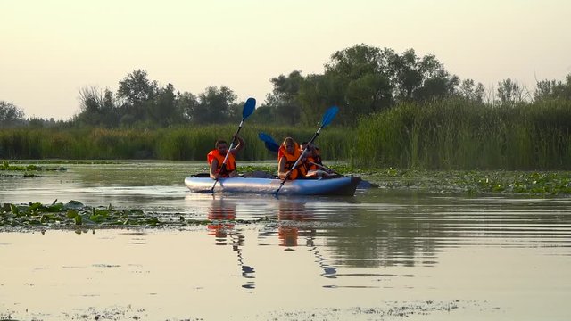 Canoeists paddle along the river. Slow motion