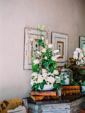 An interior element in the house with  old books, floral compositions and pictures framed on the walls