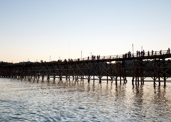 Fototapeta premium Beautiful sunset scene at old an long wooden bridge Asian wooden bridge Kanchanaburi province, Thailand