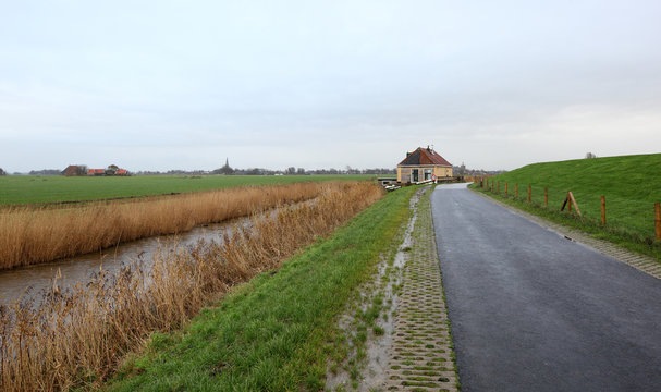 little house and flat land behind a dike in The Netherlands