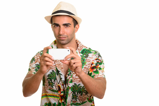 Young handsome Persian tourist man taking picture with phone