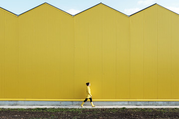 Woman walking by yellow building