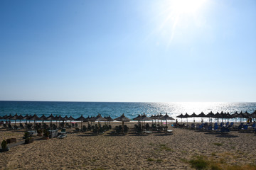 Obraz premium Beach umbrellas and sunbeds on Greece. Summer beach with parasols