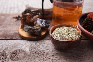 Herbal tea, homeopathy, alternative medicine, occult ritual concept/ Dry leaves in ceramic cup, stones, teapot on vintage wooden background, witchtable closeup