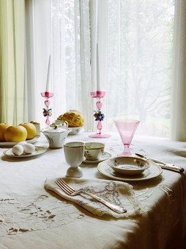 Fancy old-fashioned table set with dinnerware, candlesticks, and food.