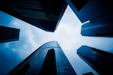 Bottom view of modern skyscrapers in business district against blue sky.