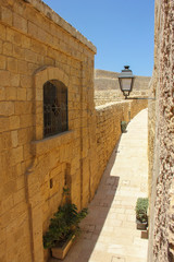 Room view from window in old town to narrow ancient street with lantern in sunny day under blue sky