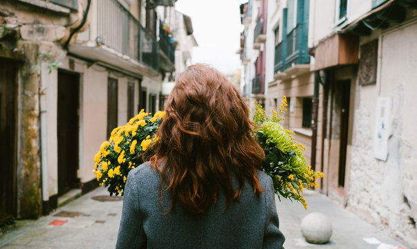 woman in the street wit a bouquet of yellow flowers