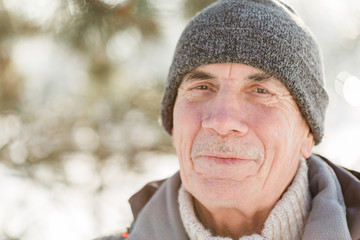 Portrait of senior man poles in winter  park. Healthy lifestyle concept. Mature man resting after...