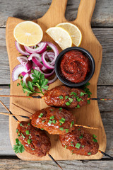 Tasty kebab with vegetables on a plate and sauce on the table. 