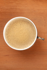 An overhead photo of coffee in a retro cup, shot from above on a rustic wooden background with copy space