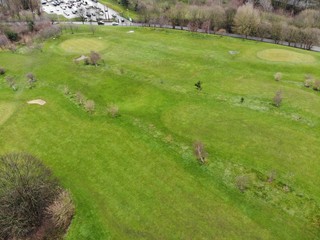 Aerial shot of a Golf course showing houses and trees with green grass.