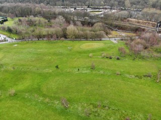 Aerial shot of a Golf course showing houses and trees with green grass.