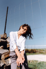 A close-up fashion portrait of a beautiful girl near a wooden house by the lake poses and relaxes at sunset. Emotional portrait of a girl