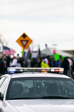 Protest: Patrol Car With Flashing Lights In Front Of Protesters