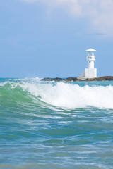 Ocean waves and white lighthouse in the background.