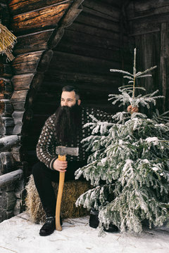 Good-Looking Bearded Man in Norwegian Knitwear Holding Axe and C