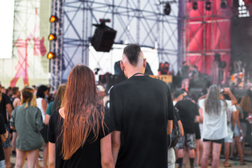 young man and woman are standing nearby at a concert of street rock music