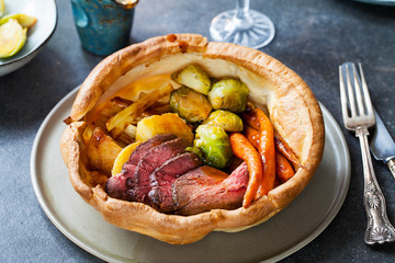 Roast dinner with beef, carrots, brussel sprouts in giant yorkshire pudding