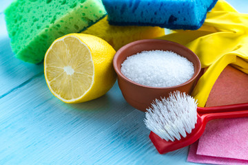 Lemon acid in a small plate, a juicy lemon, sponge for washing dishes, brushes and yellow rubber...