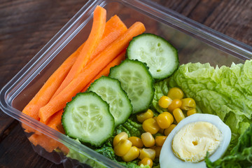 Healthy meal in a plastic container. Snack in the office, at work. Lunch box of cucumbers, buckwheat, carrots, eggs, lettuce and canned corn. Nutrition and healthy food concept