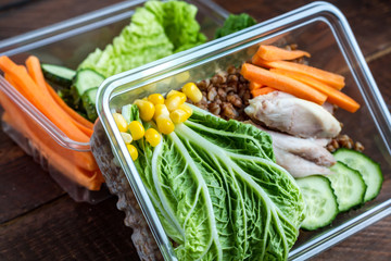 Dietary meal in a plastic container. Snack in the office, at work. Lunch box of cucumbers, buckwheat, meat, carrots, eggs, lettuce and canned corn. Nutrition and healthy food concept