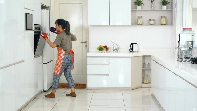 Attractive young woman baking cake and dancing in the kitchen at home. Shot in 4k resolution