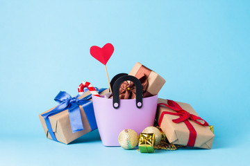 Small plastic bag for shopping, gift boxes, heart on a stick, blue background. Concept of pre-holiday shopping, gifts for friends and relatives, Christmas sale, Valentine's Day