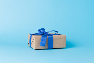 Gift box with blue ribbon on a blue background. Minimalism. Concept of a gift for loved ones