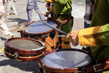 Musicians playing drums through the streets of an old city.
