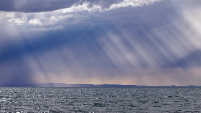 Rain and the sun's rays through the dramatic clouds in the sky over mongolian lake Durgen Nuur in Mongolia.