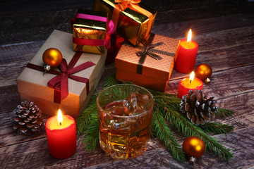 Glass with cognac or whiskey, Christmas balls and candles. New Year's tree, balls and glass with alcohol.