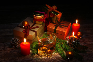 Glass with cognac or whiskey, Christmas balls and candles. New Year's tree, balls and glass with alcohol.