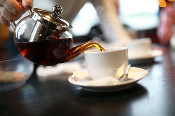 Person pouring tea into cup