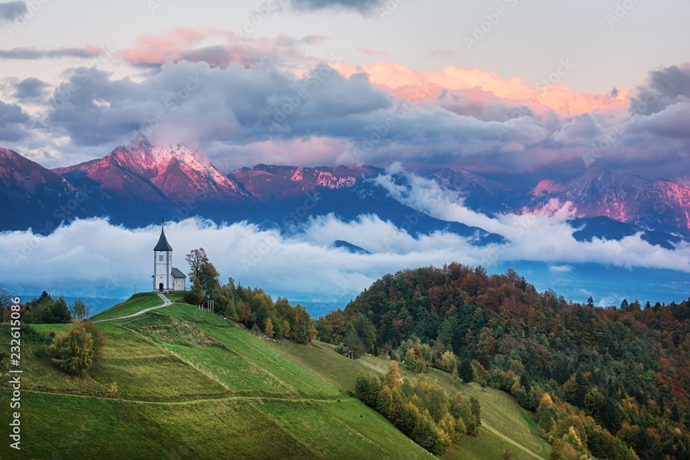 Wall mural Beautiful sunrise landscape of church Jamnik in Slovenia with cloudy sky