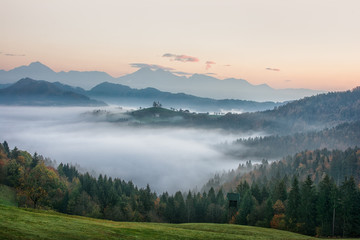 Fototapeta na wymiar Beautiful sunrise landscape of Saint Thomas Church in Slovenia on hilltop in the morning fog