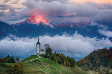 Beautiful sunrise landscape of church Jamnik in Slovenia with cloudy sky - obrazy, fototapety, plakaty