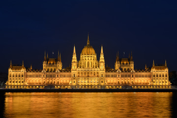 Fototapeta na wymiar Night cityscape of illuminated Budapest parliament building with golden reflection in Danube river