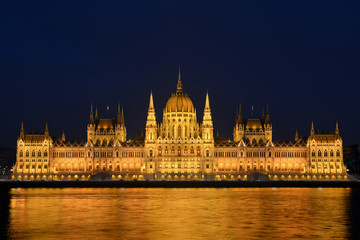 Naklejka premium Night cityscape of illuminated Budapest parliament building with golden reflection in Danube river