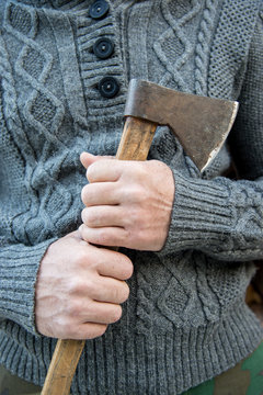 Man in a wool winter sweater holding an ax