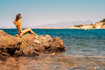 Fototapeta na wymiar young girl on the rocks by the sea