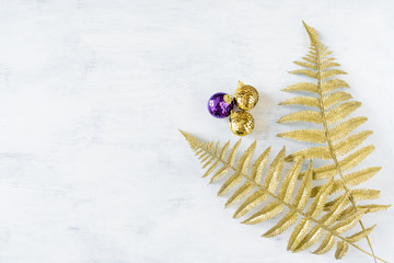 Christmas holiday festive theme with golden violet Christmas ornament and gold decorative fern leaves. Xmas composition decoration on white background, mockup, copy space