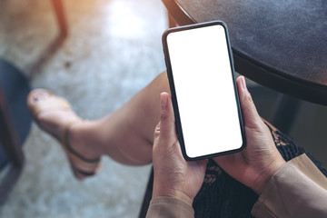 Mockup image of woman's hands holding black mobile phone with blank white screen while sitting in cafe