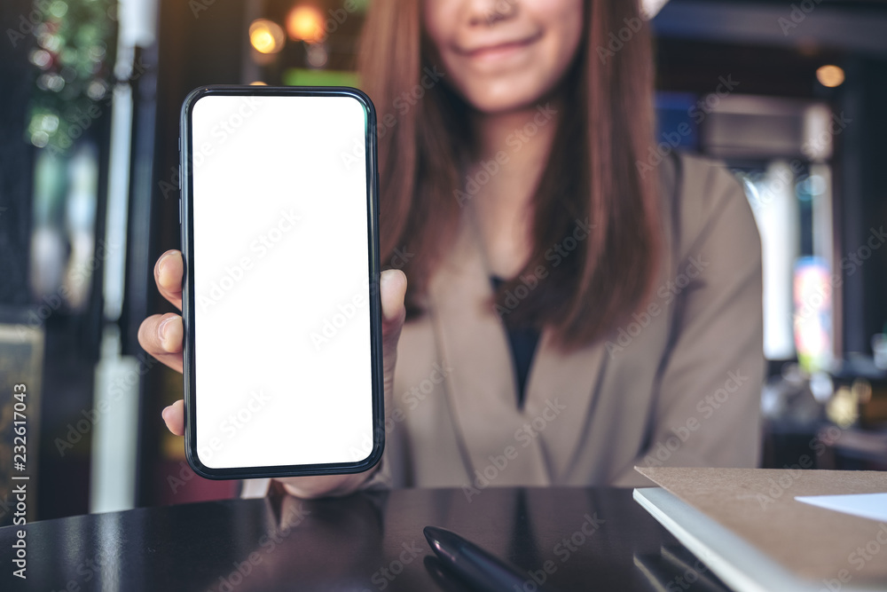 Wall mural mockup image of an asian businesswoman holding and showing black mobile phone with blank white scree