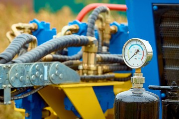 Closeup of manometer, measuring gas pressure. Pipes and valves on the background. Selective focus.