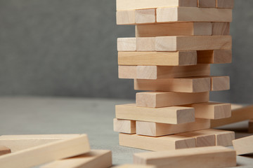 Tower of wooden blocks on gray background. Board game for the whole family or party. Concept of building business or building team.