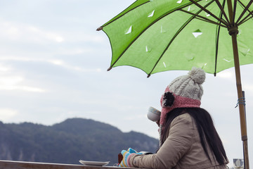 People sitting in winter clothes drinking coffee on the balcony,there is a mountain in front of him, relax and travel.