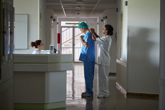 Hospital assistant helping doctor with the protection clothing